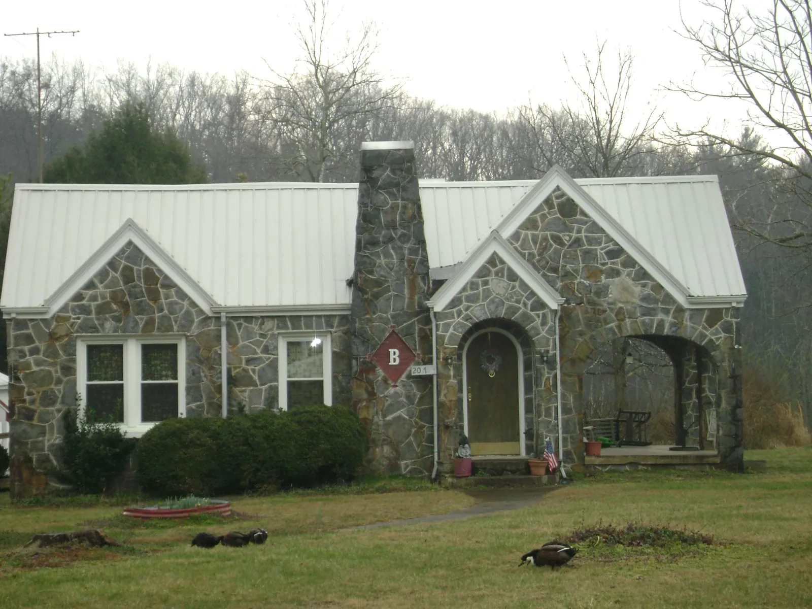 White metal roof on a stone cottage with steep gables in Stillwater