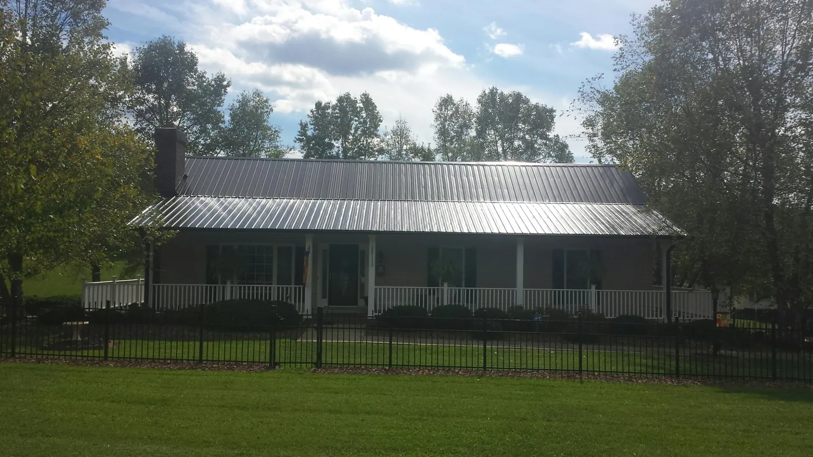 Gray metal roof on a brick ranch with a full width front porch — Gutter Guard Installation work by our crew in Stillwater
