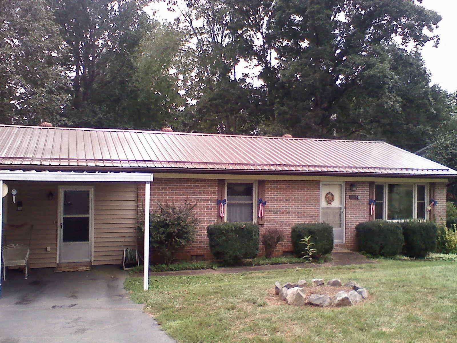 Bronze metal roof and carport on a brick ranch home — Roof Repair work by our crew in Stillwater